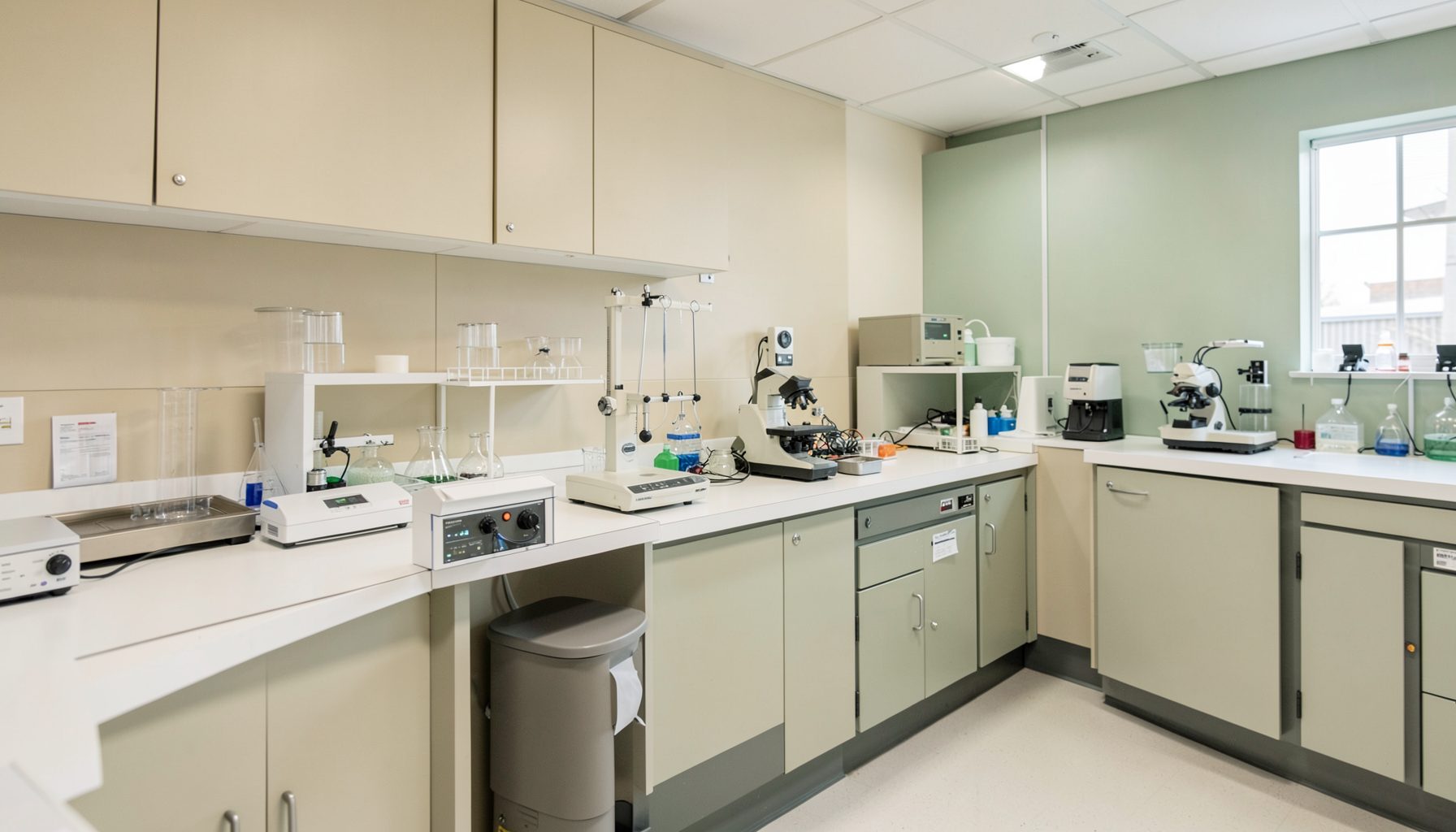 A clean, well-organized laboratory workspace with neutral beige and soft green tones, conveying precision and advanced quality practices.